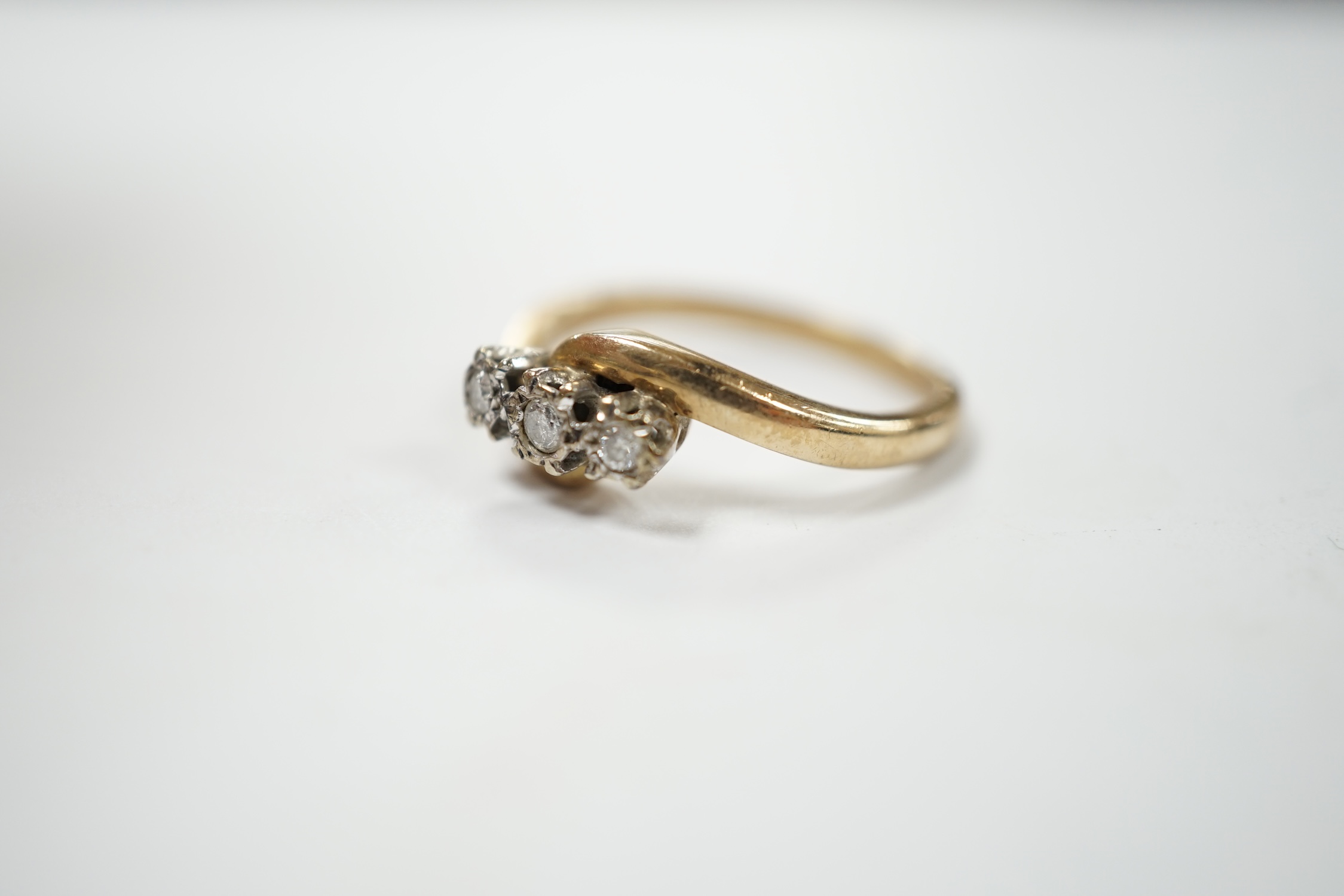 A modern 9ct gold and three stone diamond set cross-over ring, size P/Q, gross weight 3.4 grams. Condition - fair